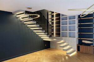 Rénovation complète d'une villa haute de gamme à Pessac - séjour avec escalier aérien en béton ciré, bibliothèque sur-mesure, et parquet pointe de hongrie