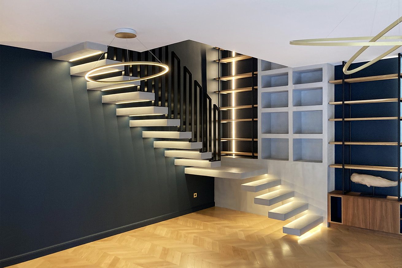 Rénovation complète d'une villa haute de gamme à Pessac - séjour avec escalier aérien en béton ciré, bibliothèque sur-mesure, et parquet pointe de hongrie